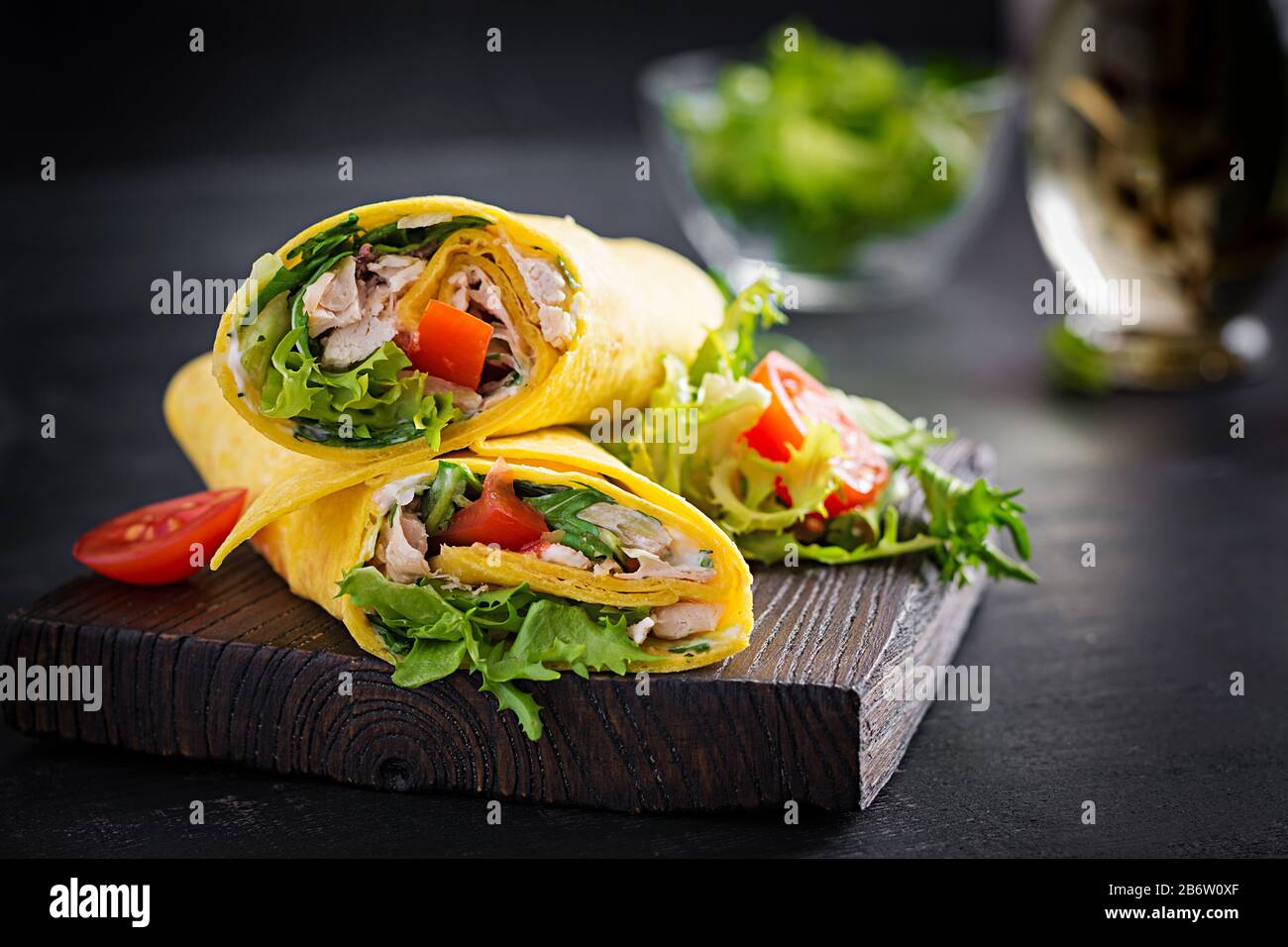 Tortilla fraîche avec poulet et légumes frais sur planche en bois. Burrito de poulet. Cuisine mexicaine. Espace de copie Banque D'Images