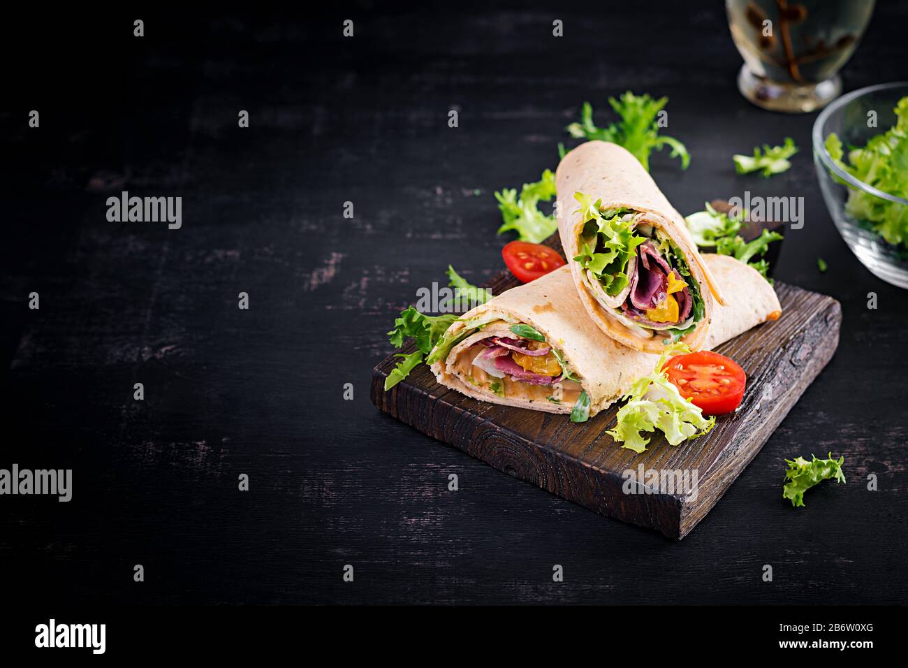 Tortilla fraîche avec du bœuf au jambon et des légumes frais à bord en bois. Burrito de boeuf. Cuisine mexicaine. Espace de copie Banque D'Images