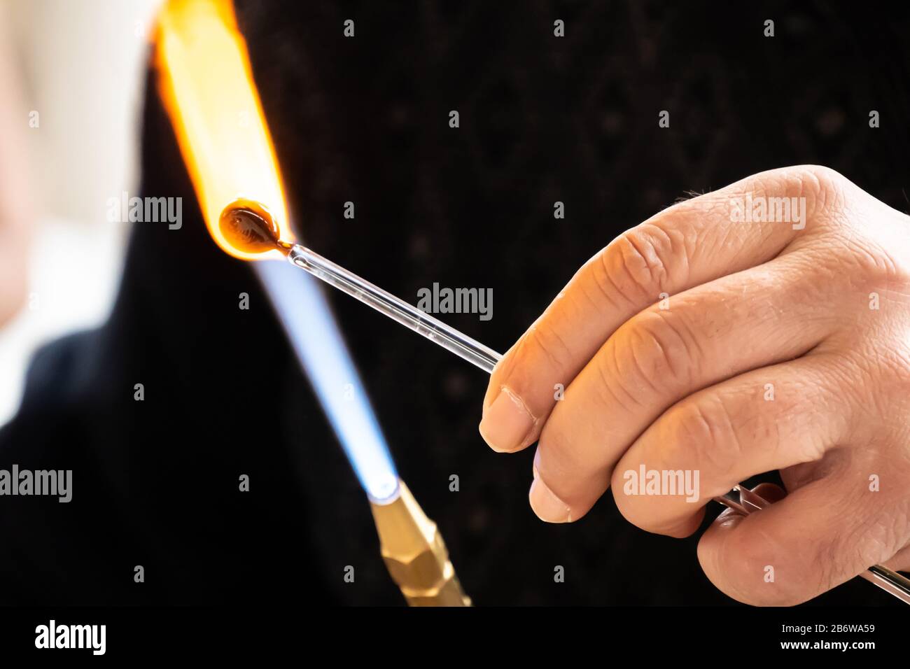 Mains de l'homme d'artisanat faisant un objet de verre d'artisanat. La machine à verre qui travaille du verre fondu avec une torche flamboyante. Gros plan de la flamme de la torche Banque D'Images