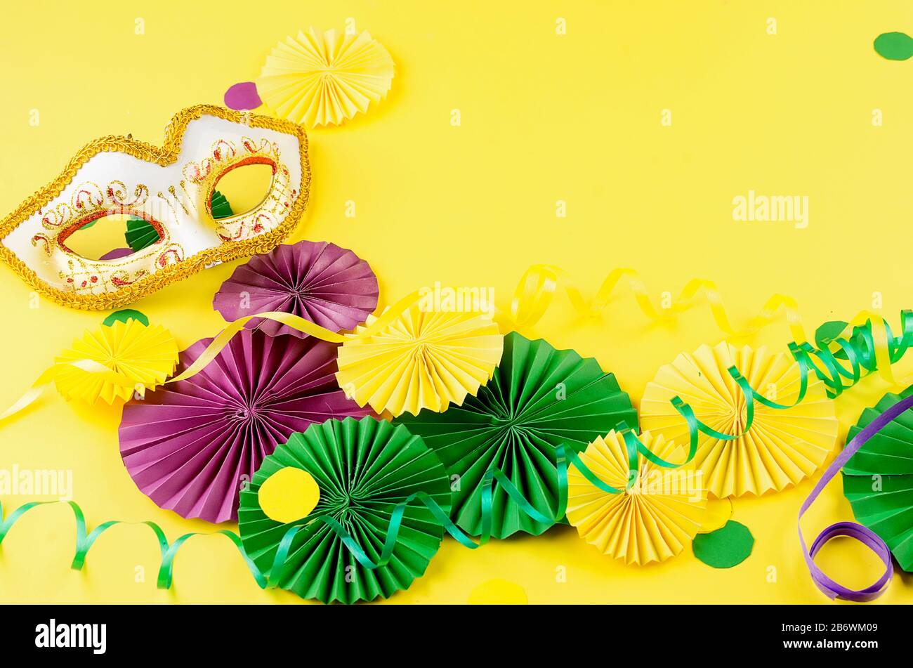 Papier coloré confetti, masque carnivale et serpentine colorée sur un fond jaune avec espace de copie, carte de vœux et modèle d'invitation de fête des Banque D'Images