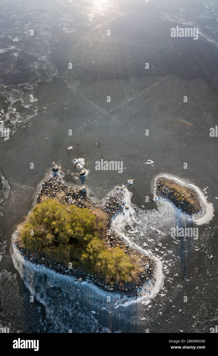 Vue aérienne verticale d'une petite île avec glace translucide fissurée couvrir l'environnement Banque D'Images