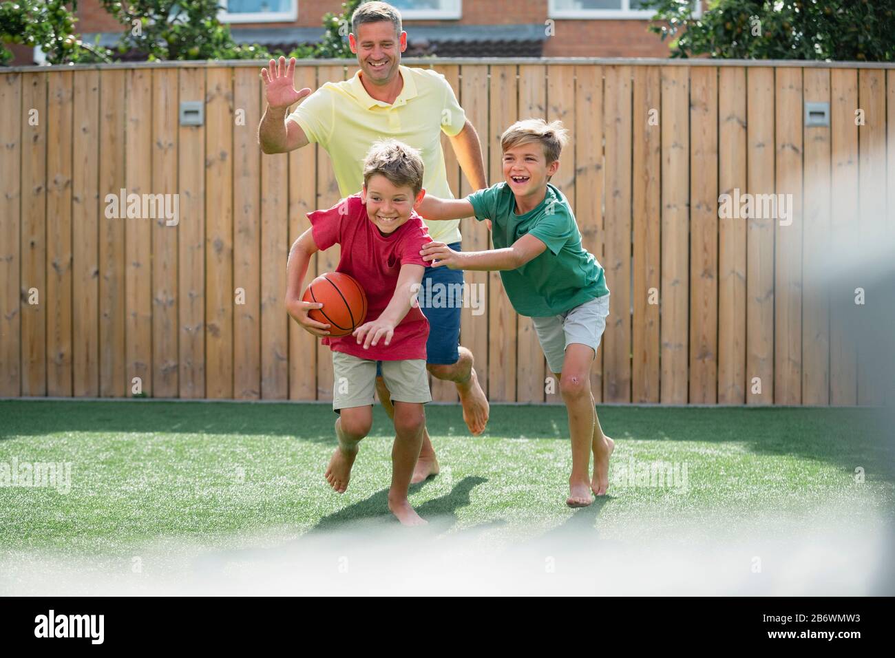 Une photo d'une famille de garçons jouant avec un basket-ball dans la cour arrière. Banque D'Images