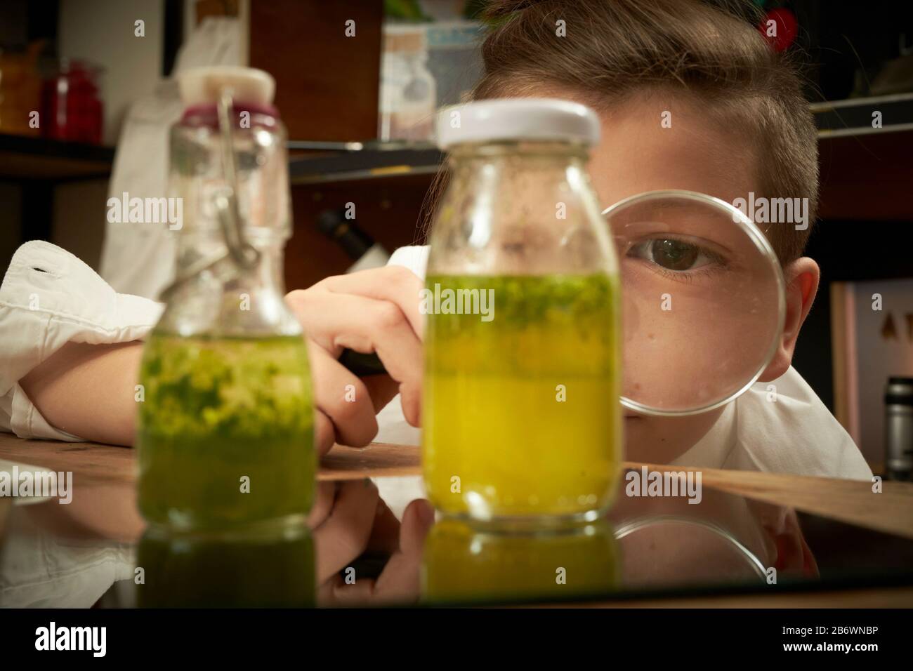 Enfants enquêtant sur la nourriture. Un garçon fait de l'huile imprégnée d'herbes. Apprentissage selon le principe de la pédagogie Reggio, compréhension et découverte ludiques. Allemagne Banque D'Images