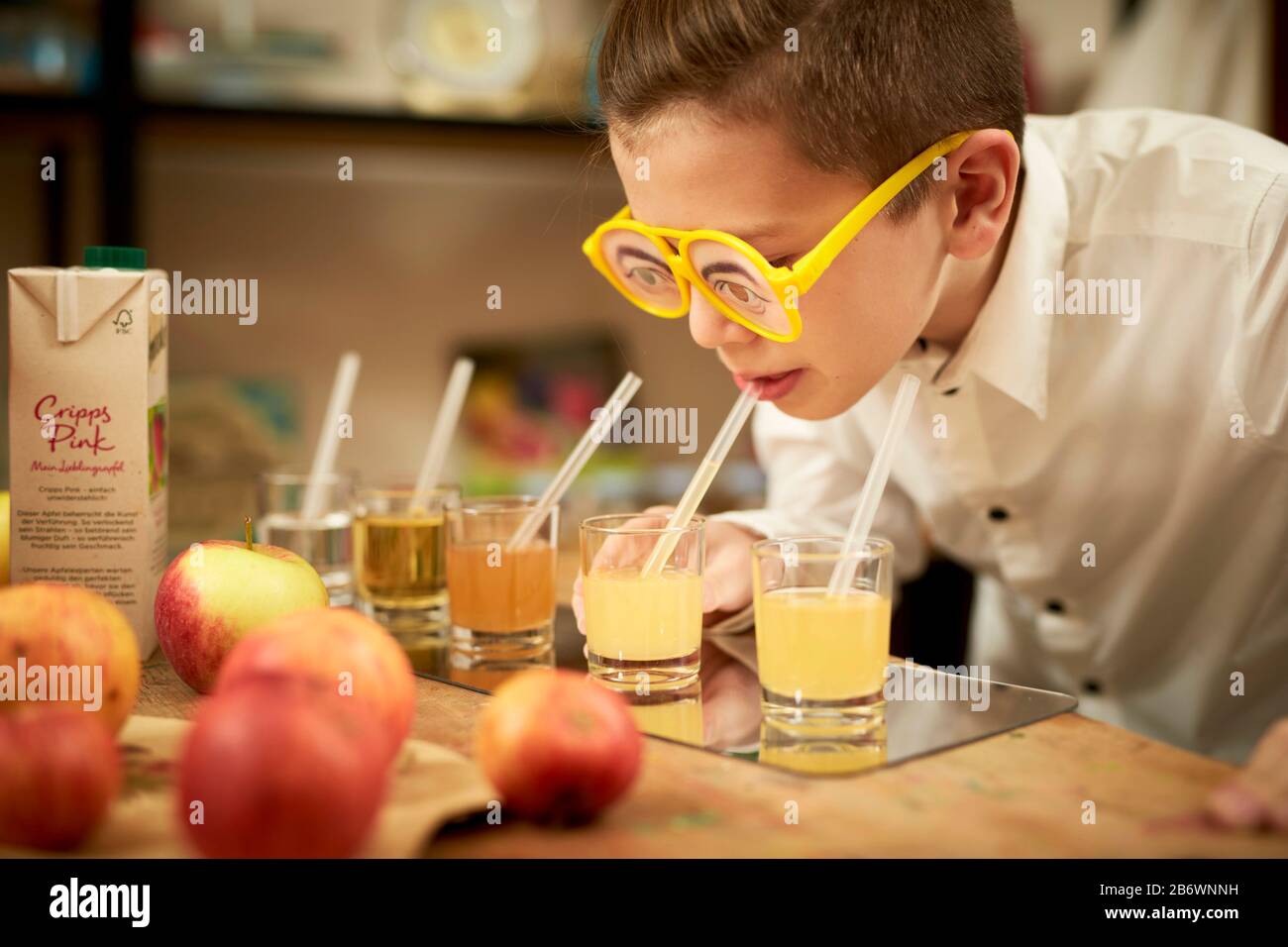 Enfants enquêtant sur la nourriture. Un garçon fait une dégustation aveugle de divers jus de fruits. Apprentissage selon le principe de la pédagogie Reggio, compréhension et découverte ludiques. Allemagne. Banque D'Images