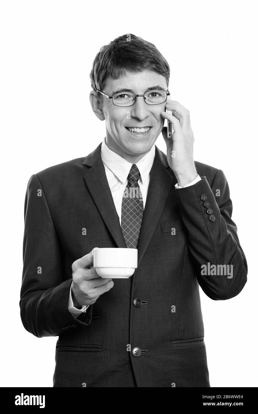 Un homme d'affaires heureux souriant tout en parlant sur le téléphone portable et en tenant une tasse de café Banque D'Images