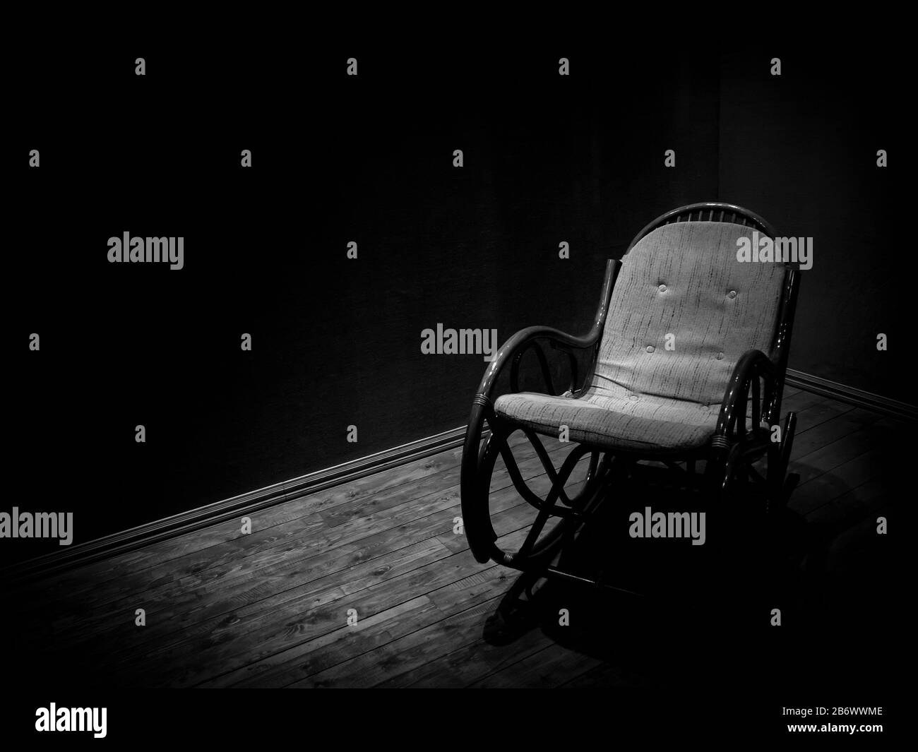 Chaise rocking en osier dans une chambre vide avec parquet, style minimaliste monochrome Banque D'Images