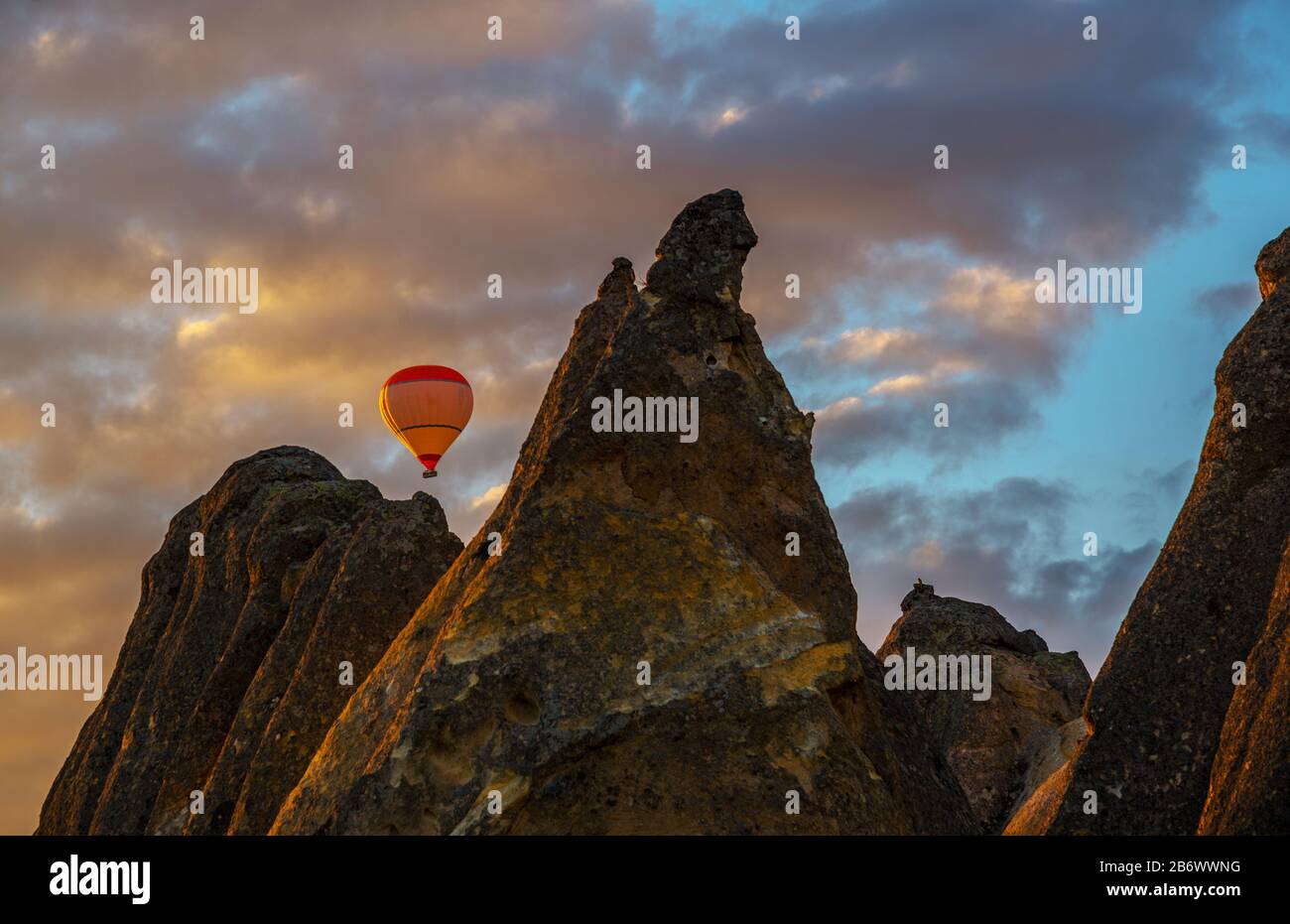 Vol de montgolfières contre le fond du ciel au lever du soleil. Arrangements de roches de Cappadoce en premier plan. Banque D'Images