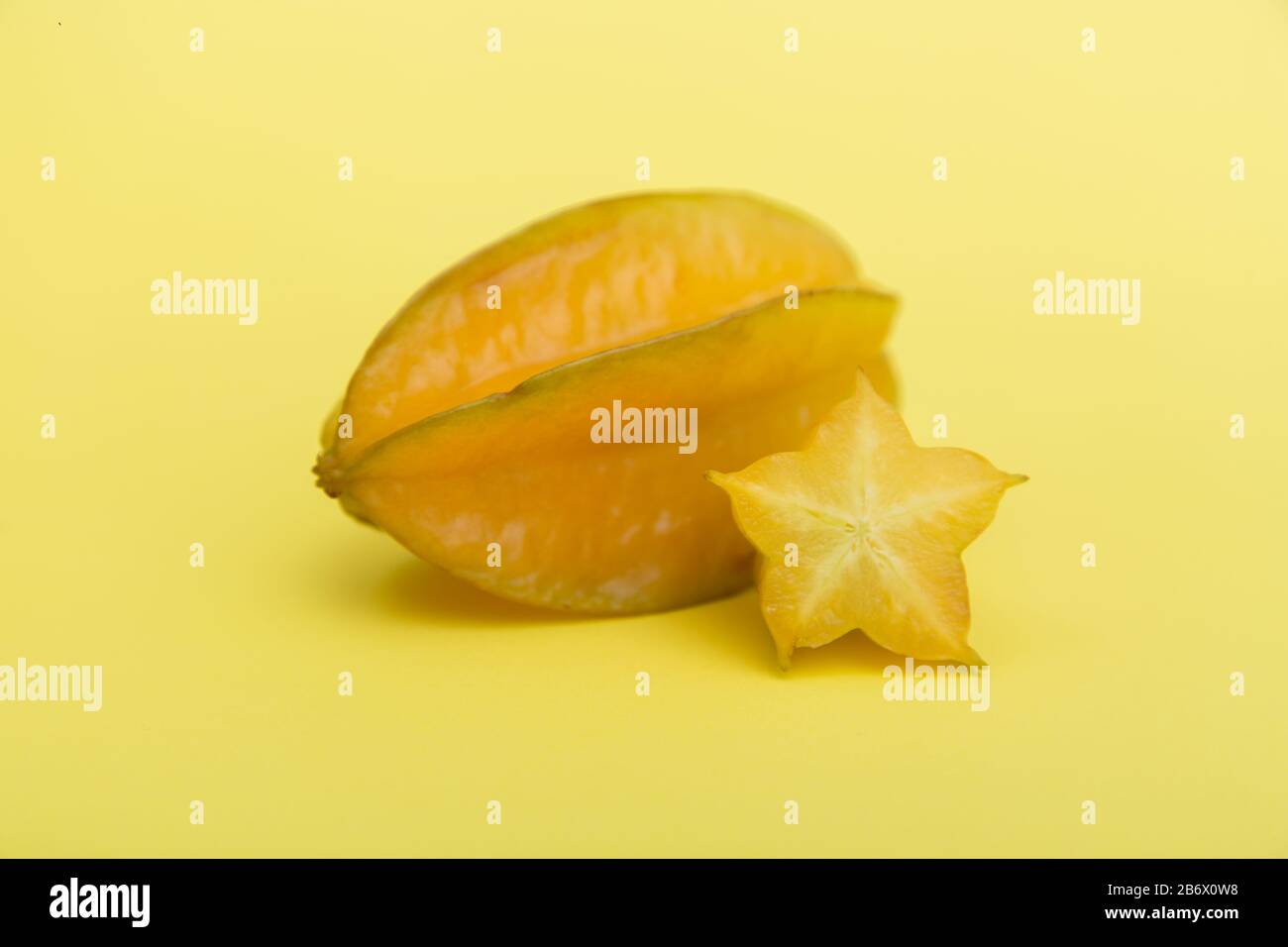 Carambola aux fruits étoiles ou aux fruits de la étoile avec tranche sur fond jaune. Des fruits sains. Banque D'Images