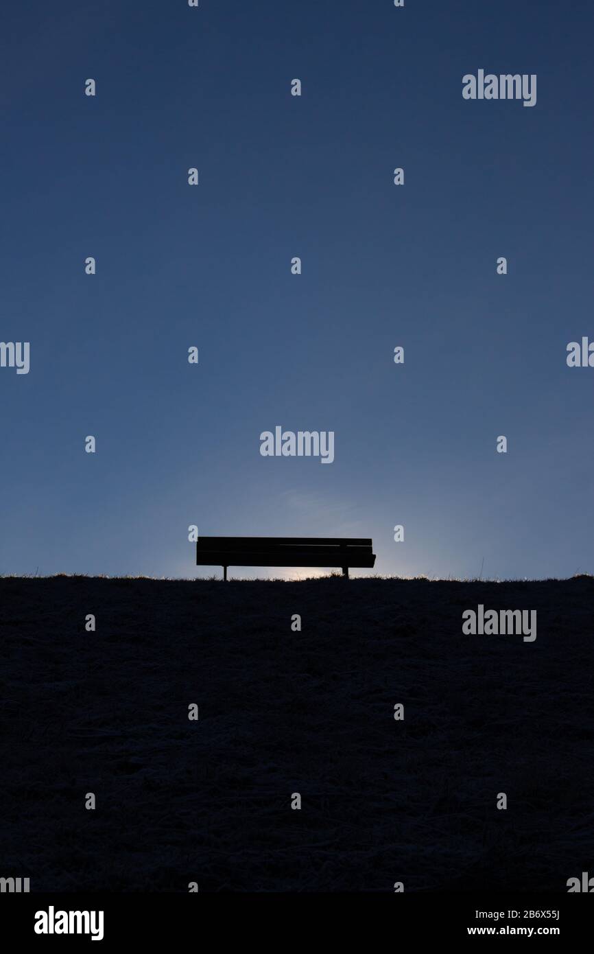 Silhouette d'un banc vide sur une colline avec un ciel bleu clair Banque D'Images