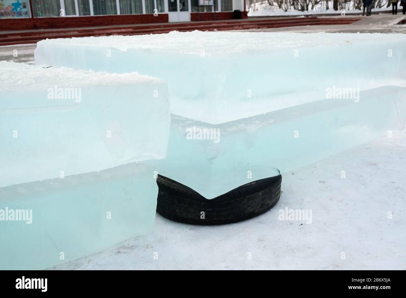 Les blocs de glace se trouvent sur les pneus en caoutchouc. Pneus noirs en tant que support. Glace pour construire une ville de glace Banque D'Images Les blocs de glace se trouvent sur les pneus en caoutchouc. Pneus noirs en tant que support. Glace pour construire une ville de glace Banque D'Images