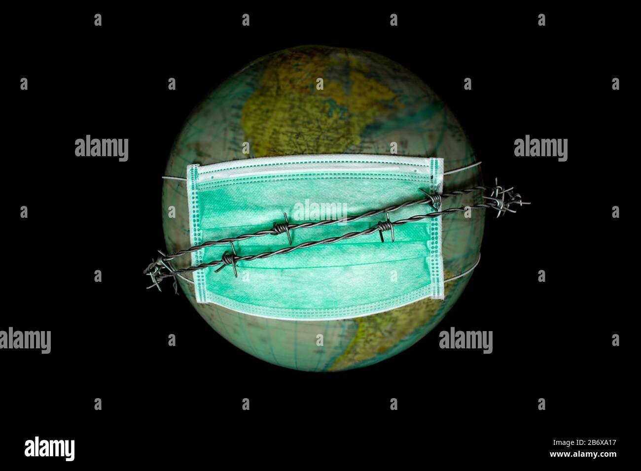 Le monde ou la terre seul dans l'espace, portant un masque médical pour se protéger de la pollution mondiale et des fils barbelés comme symbole de ne pas pouvoir quitter la terre Banque D'Images