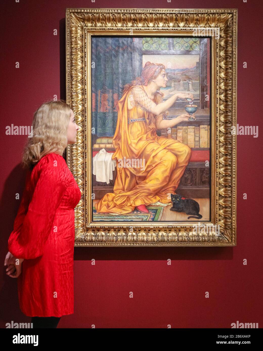Londres Royaume Uni. 12 mars 2020. Un assistant pose avec la potion de l Amour d Evelyn de Morgan representant une femme en robe orange frappante 1903 huile sur toile. The Enchanted