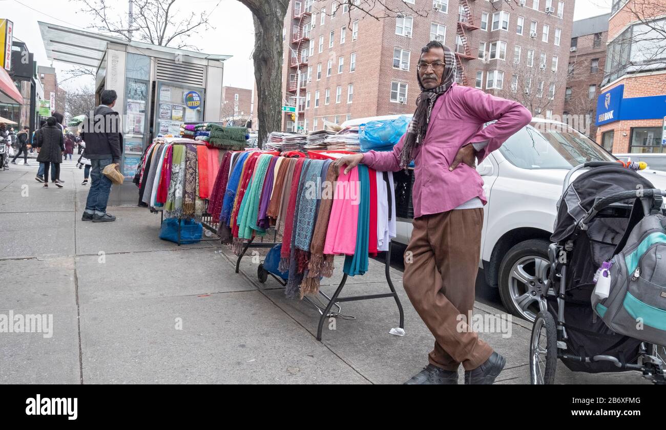 Un homme d'Asie du Sud dans un foulard, comme un musulman, vendant des  vêtements et des tissus à partir d'une table extérieure sur la 37ème Avenue  à Jackson Hrights, Queens, New York