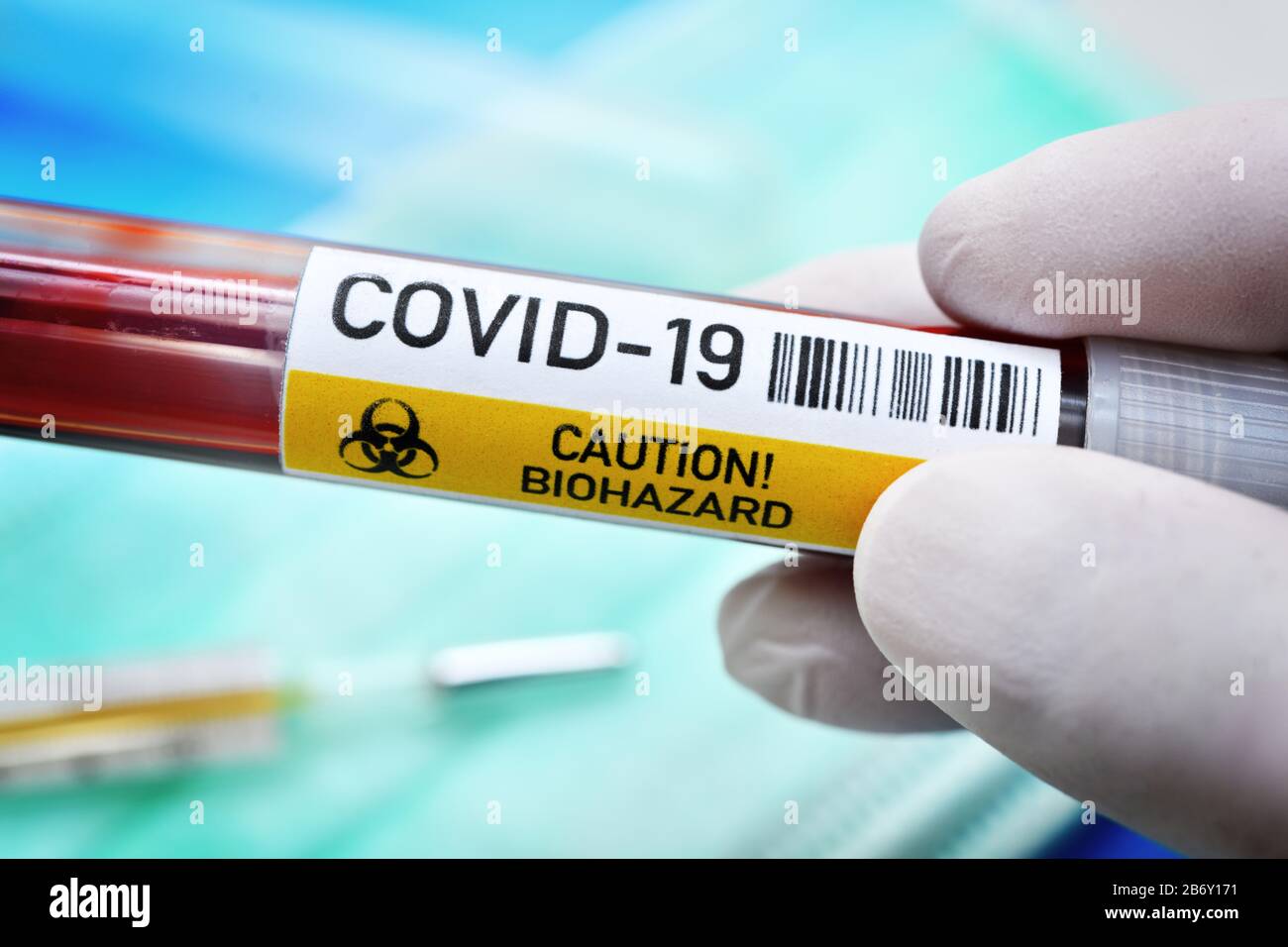 Main mit Latexhandschuh haelt Blutentnahmeroehrchen mit Aufschrift Covid-19, Symbolfoto Coronavirus Banque D'Images