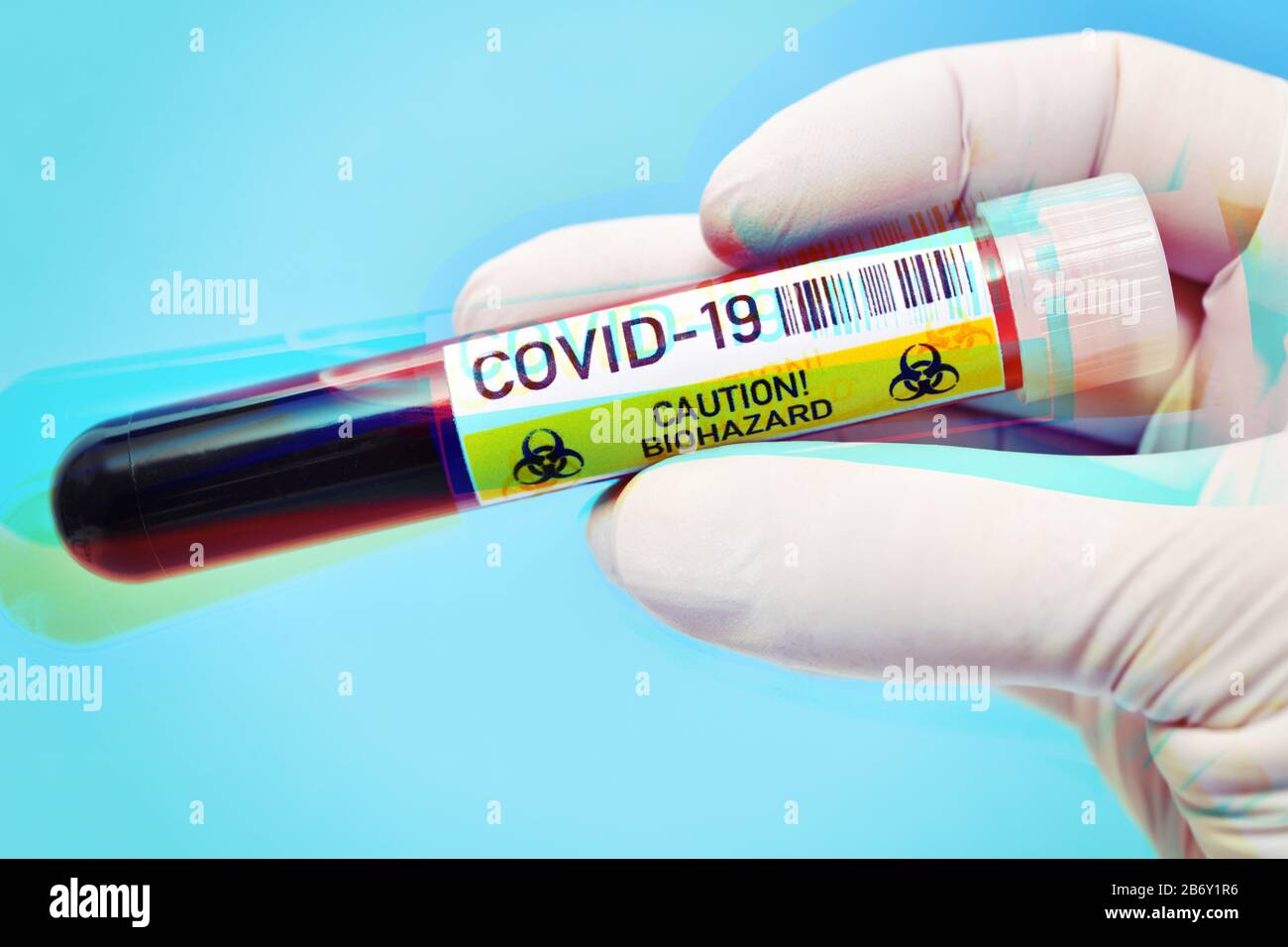 Main mit Latexhandschuh haelt Blutentnahmeroehrchen mit Aufschrift Covid-19, Symbolfoto Coronavirus Banque D'Images
