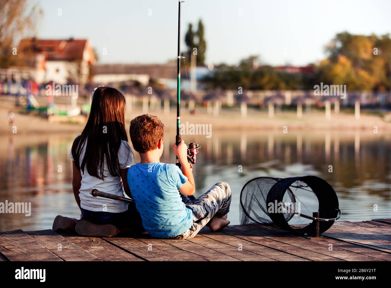 Deux jeunes petits amis mignons, un garçon et une fille pêchant sur un lac lors d'une journée d'été ensoleillée. Les enfants jouent. Amitié. Banque D'Images