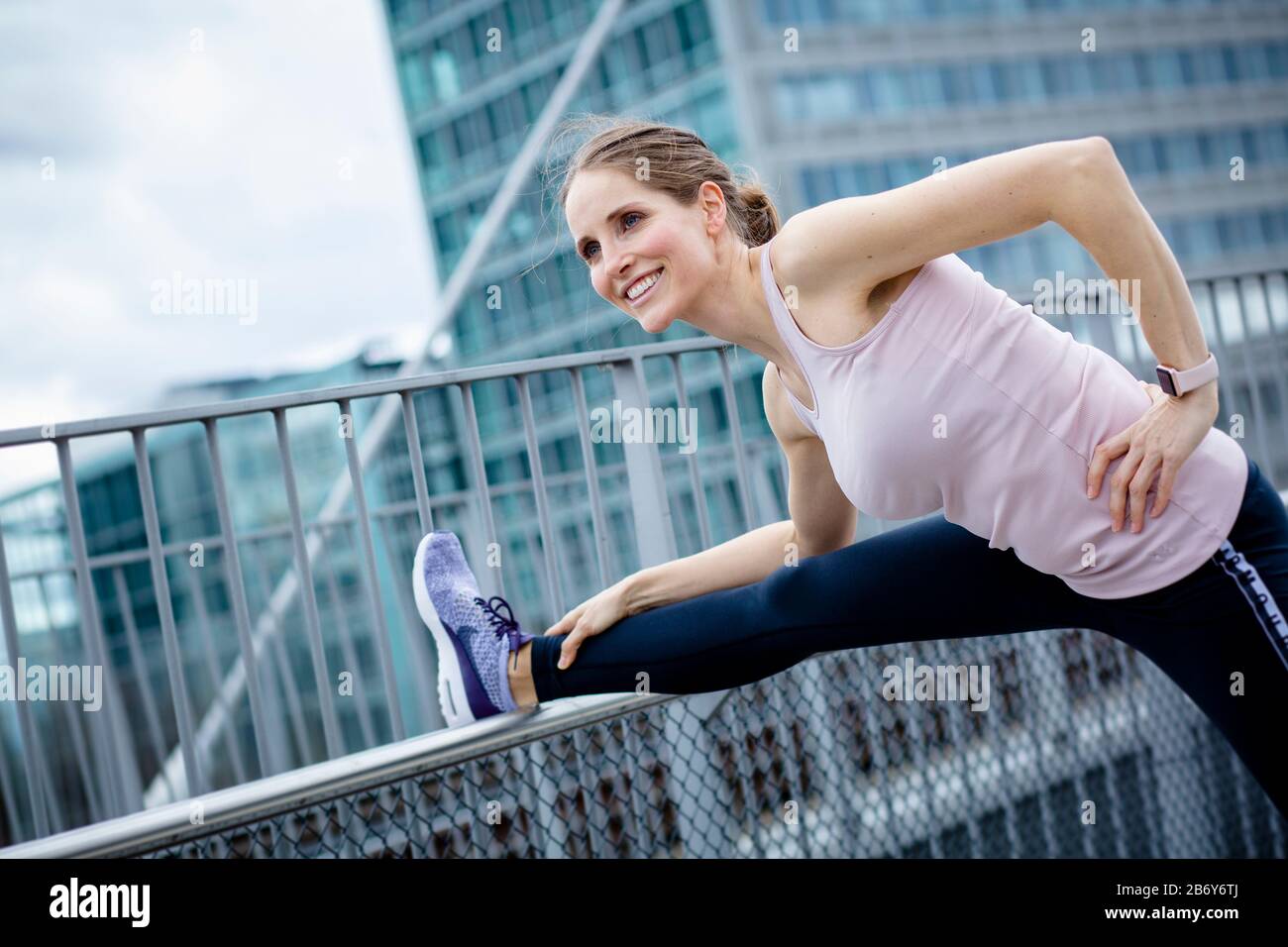 Junge Sportlerin macht Dehnübungen nach dem Sport in der Stadt. Le jeune sportif s'étire après les sports dans la ville. Banque D'Images