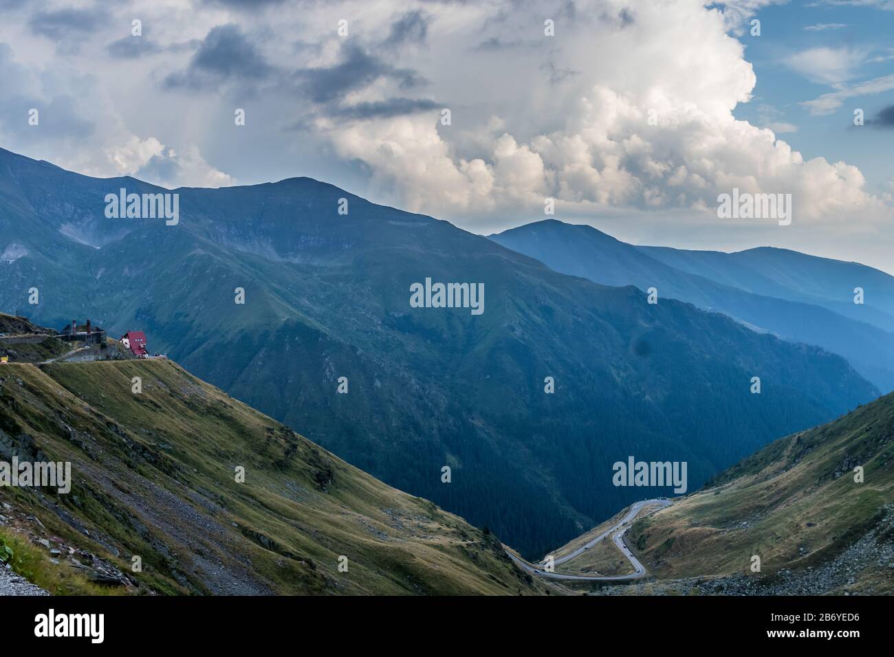 Maison de sauvetage de montagne sur le rebord d'une route de montagne avec des voitures passant par la route de montagne sinueuse au fond avec la forêt couverte haute montagne dans Banque D'Images