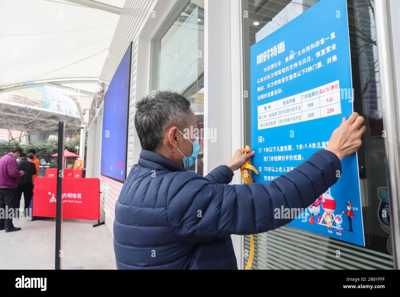 Shanghai. 12 mars 2020. Un membre du personnel affiche des informations sur les réductions de billets à l'entrée de la tour des perles orientales de Shanghai, dans l'est de la Chine, le 12 mars 2020. La tour de Shanghai, le bâtiment le plus élevé de Chine, a rouvert son attraction touristique « Top of Shanghai Observatory » à partir de jeudi. Deux autres sites touristiques ont également commencé à recevoir des touristes de jeudi, dont la tour des perles orientales de Shanghai et la tour Jinmao de Shanghai. POUR ALLER AVEC les paysages de gratte-ciel de 'Hanghai, les monuments à rouvrir' crédit: Ding Ting/Xinhua/Alay Live News Banque D'Images