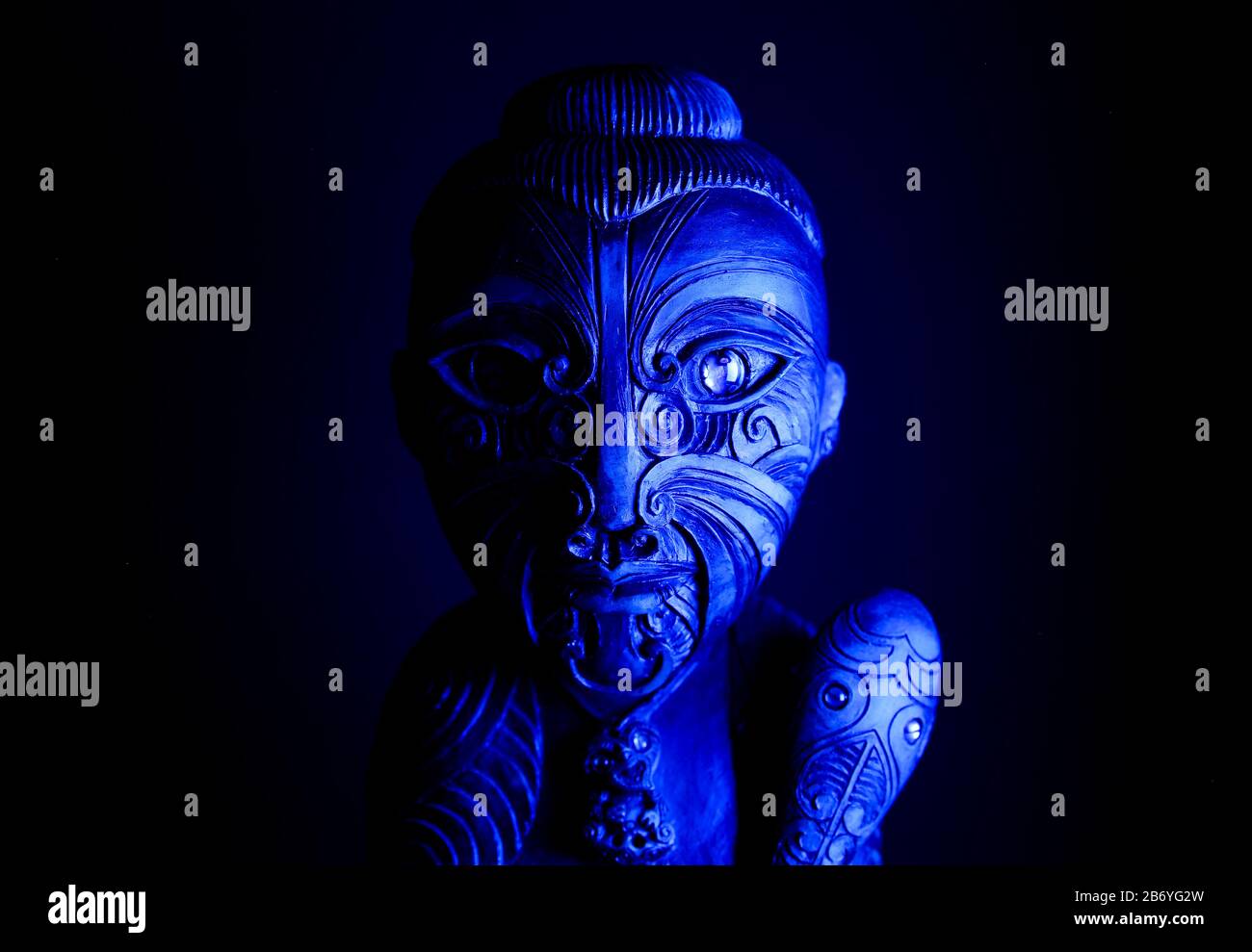 Studio de sculpture mystique en bois hawaïen tatouée avec la mace illuminée par la lumière bleue Banque D'Images