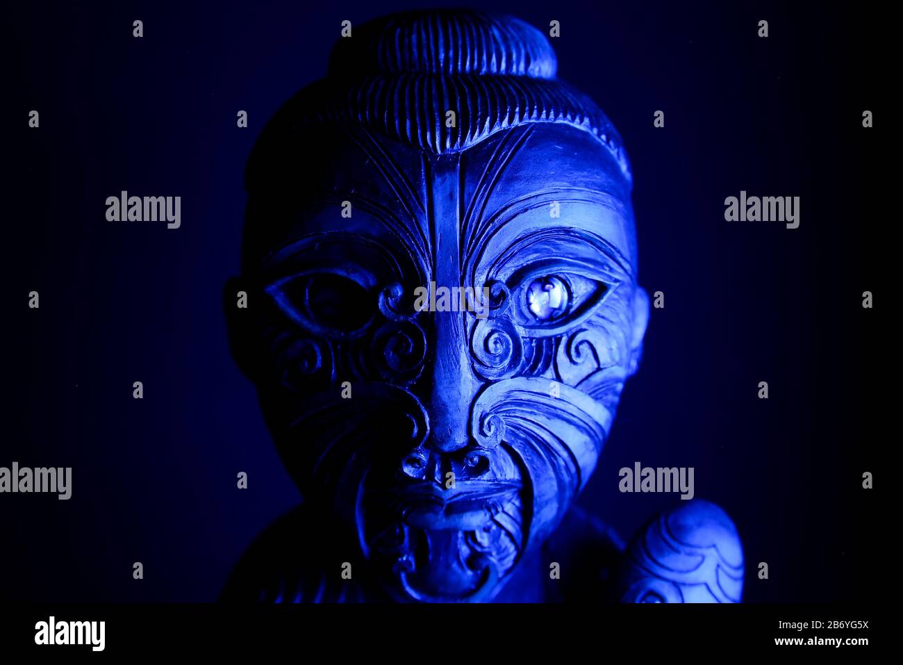 Studio de sculpture mystique en bois hawaïen tatouée avec la mace illuminée par la lumière bleue Banque D'Images
