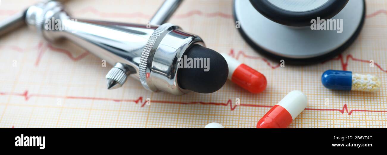 Instruments médicaux et pilules posés sur le papier d'électrocardiogramme Banque D'Images