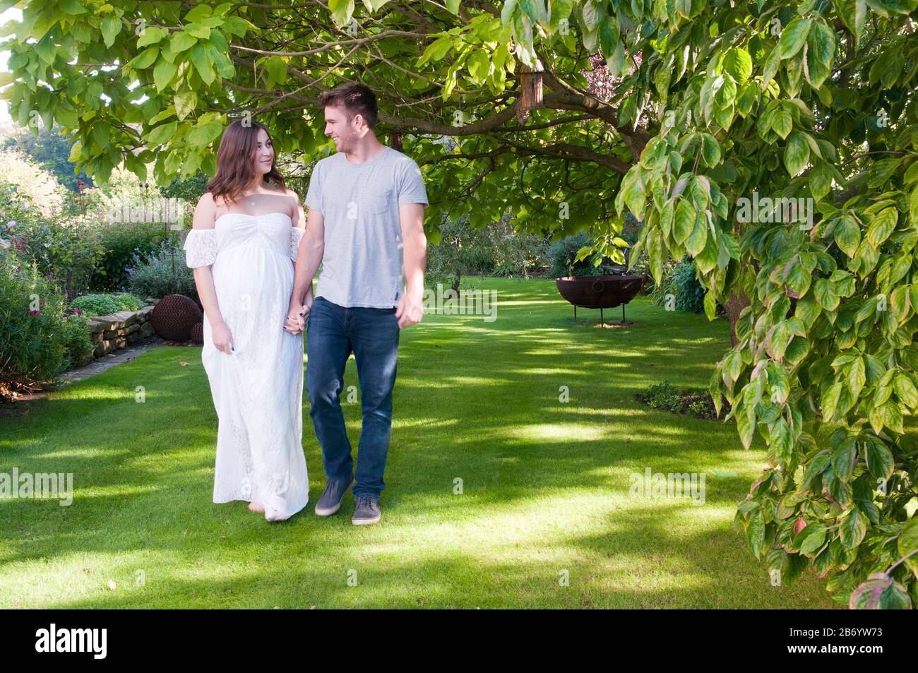 Belle jeune femme enceinte marchant main dans la main avec son partenaire un beau jour d'été Banque D'Images