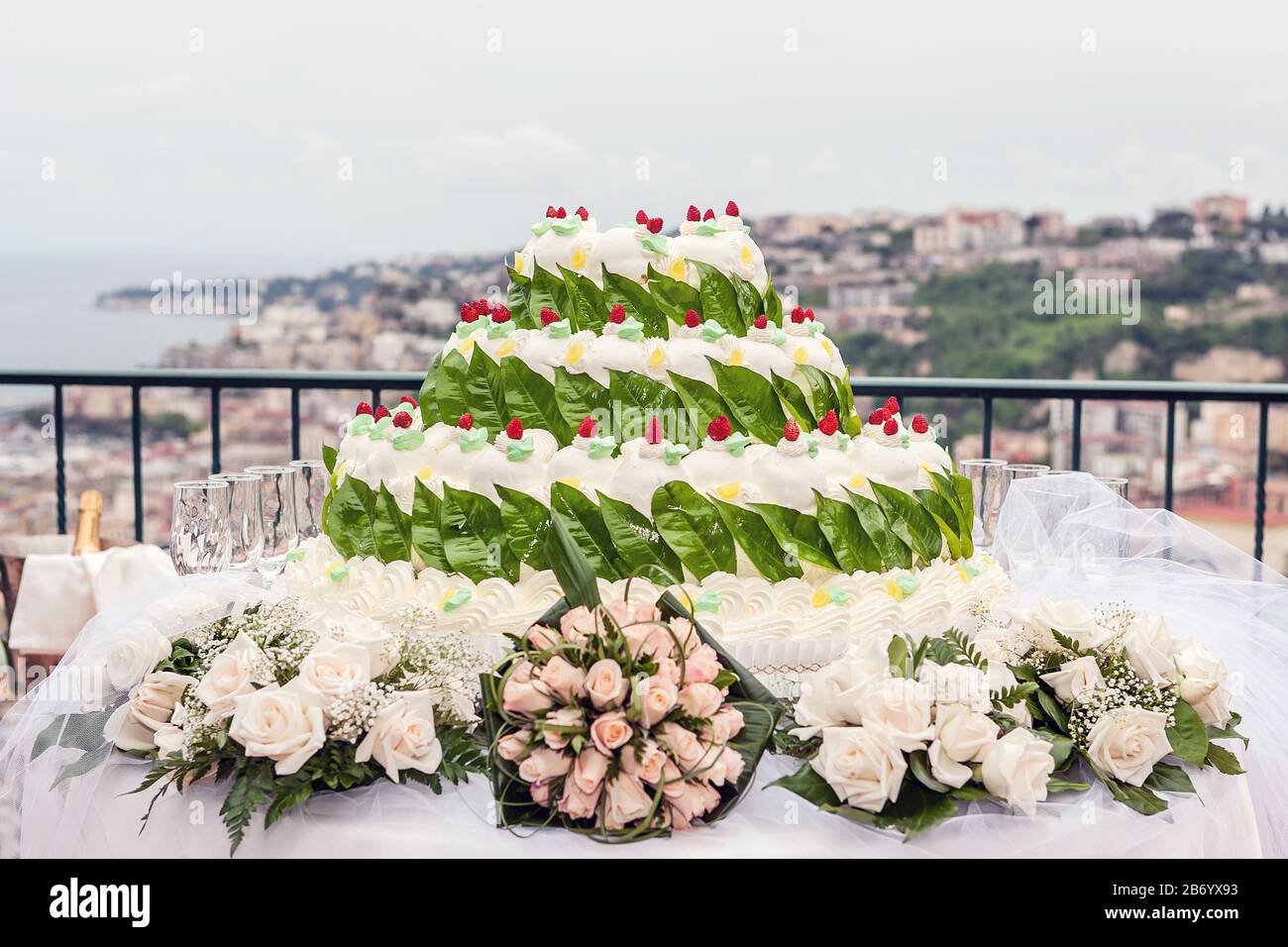 Gâteau de mariage blanc décoré de fruits rouges et de feuilles de citron vert, thème Floreal. Banque D'Images