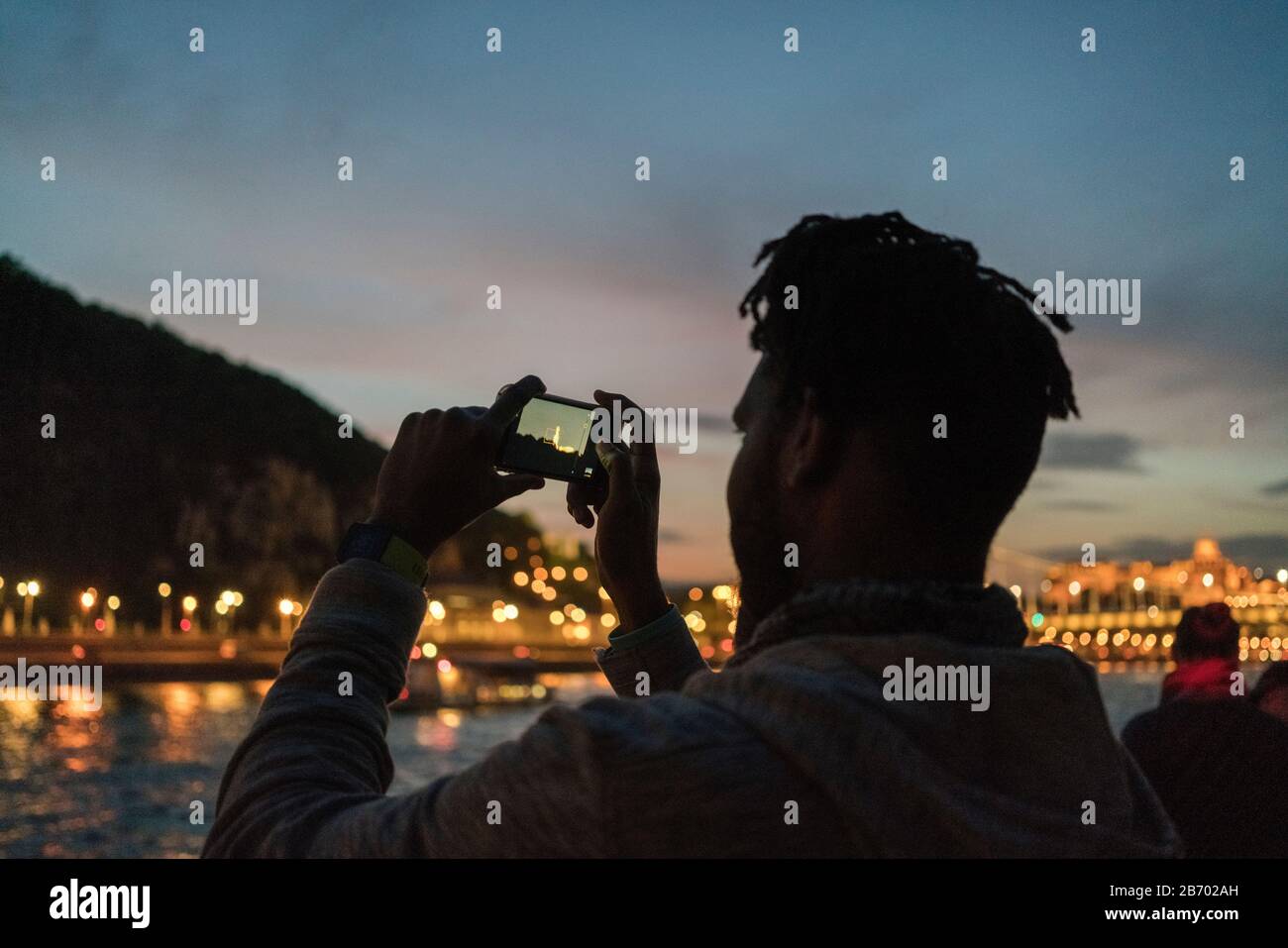 Homme africain prenant l'image d'un bateau la nuit à Budapest Banque D'Images