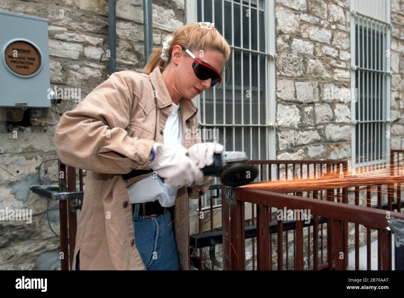 Austin, Texas, États-Unis, 1997: Soudeur féminin travaillant sur une main courante avec une meuleuse métallique à l'extérieur d'un bâtiment en centre-ville. M. ©Bob Daemmrich Banque D'Images