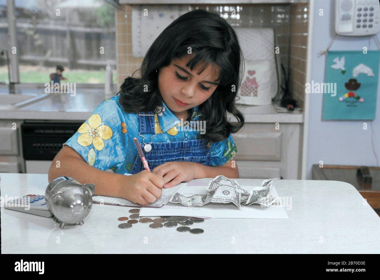 Austin Texas États-Unis, 1998 : huit ans, une jeune fille panaméenne-américaine prépare le dépôt pour le compte d'épargne à partir de dollars et de pièces qu'elle a économisé.. MR ©Bob Da Banque D'Images