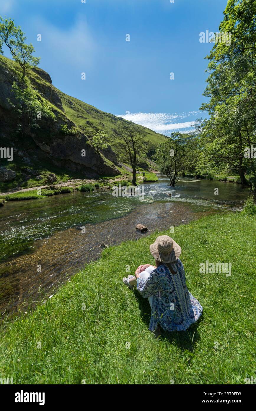 Assis en regardant la rivière Dove dans Peak District National Park, Dovedale, Derbyshire Royaume-Uni Banque D'Images