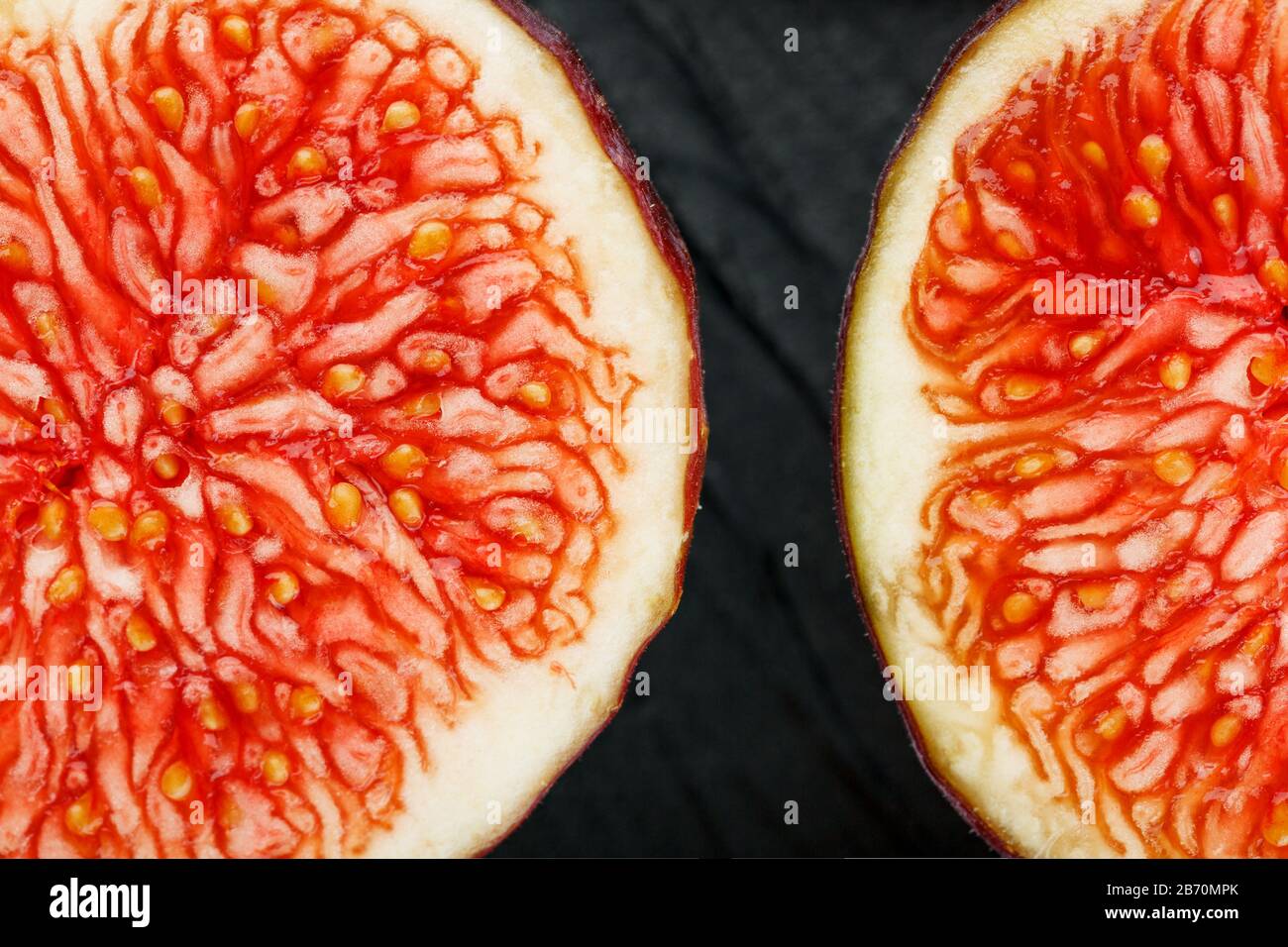Les figues sont mûres. Gros plan de fruits de figuier tranchés sous forme de texture inscrite dans un rectangle sur fond de texture noire Banque D'Images