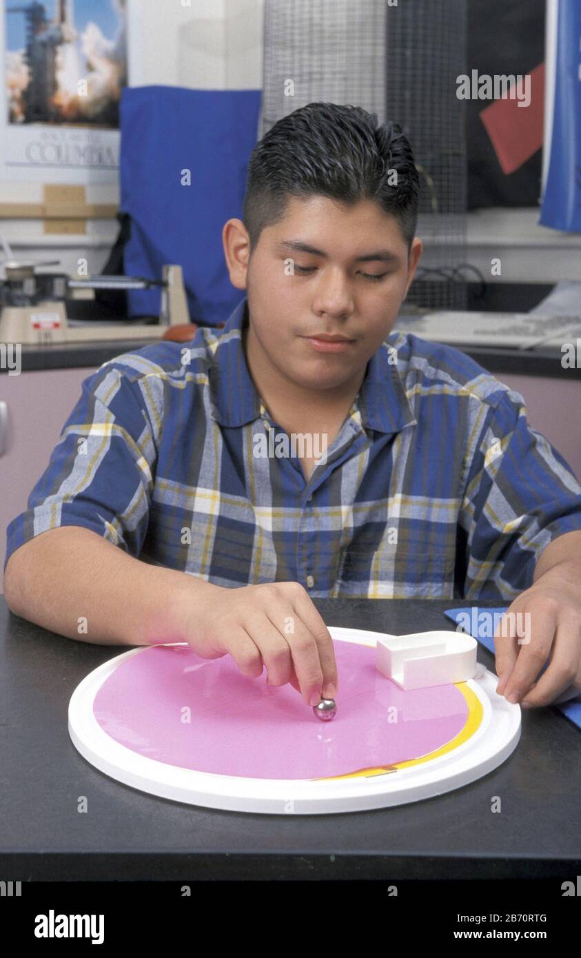 Austin Texas USA: L'adolescence hispanique roule un marbre sur une plaque tournante pour démontrer l'effet Coriolis. ©Bob Daemmrich Banque D'Images