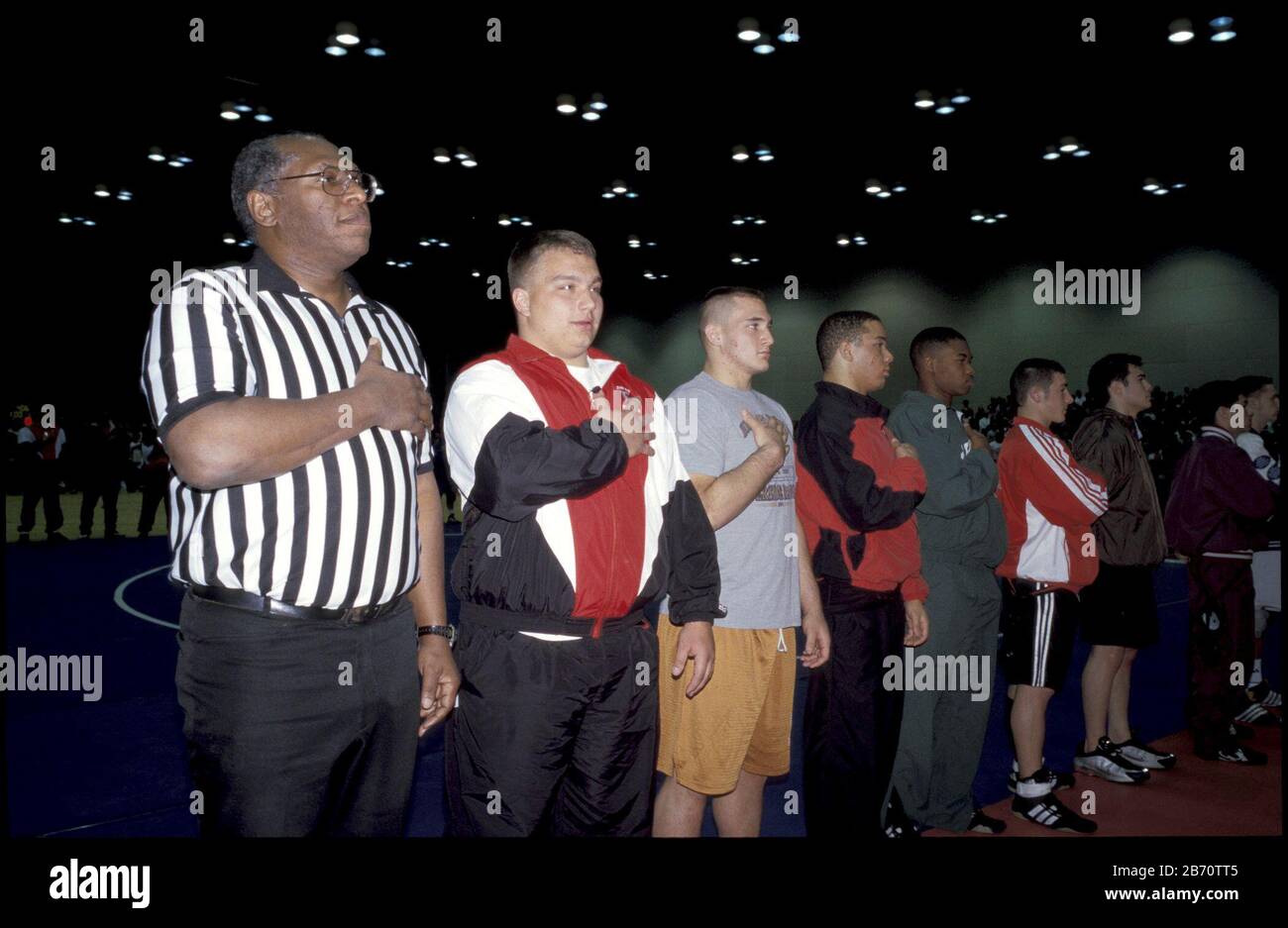 Austin, Texas États-Unis, février 2002: L'arbitre et les athlètes placent les mains sur les coeurs pendant le jeu de l'hymne national au tournoi de championnat de lutte de l'État de l'école secondaire des garçons. ©Bob Daemmrich Banque D'Images