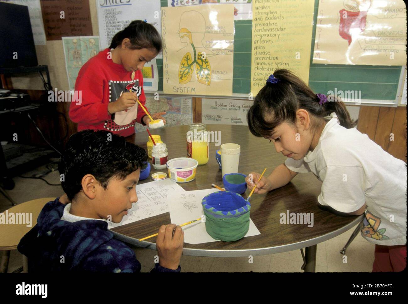 Austin Texas USA: Éducation bilingue: Étudiants en classe d'art de quatrième classe peinture indienne "peau animale" dessins sur la poterie. ©Bob Daemmrich Banque D'Images