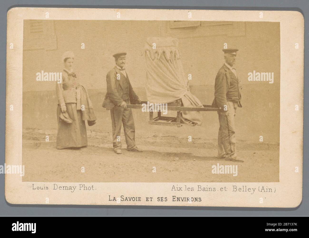 La Savoie et ses environs Twee mannen dragen een persoon in een draagstoel; een vrouw loopt erachter. Fabricant : fotograaf: Louis Demay (vermeld op object) Dating: 1870 - 1880 Dimensions: Geheel: H 71 mm × b 108 mm Banque D'Images