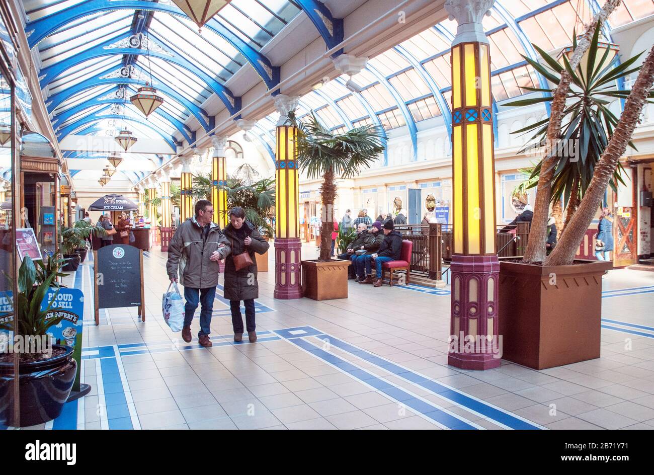 Homme et femme marchant dans le hall d'entrée en verre voûté du complexe Winter Gardens Blackpool Lancashire Angleterre Royaume-Uni Banque D'Images