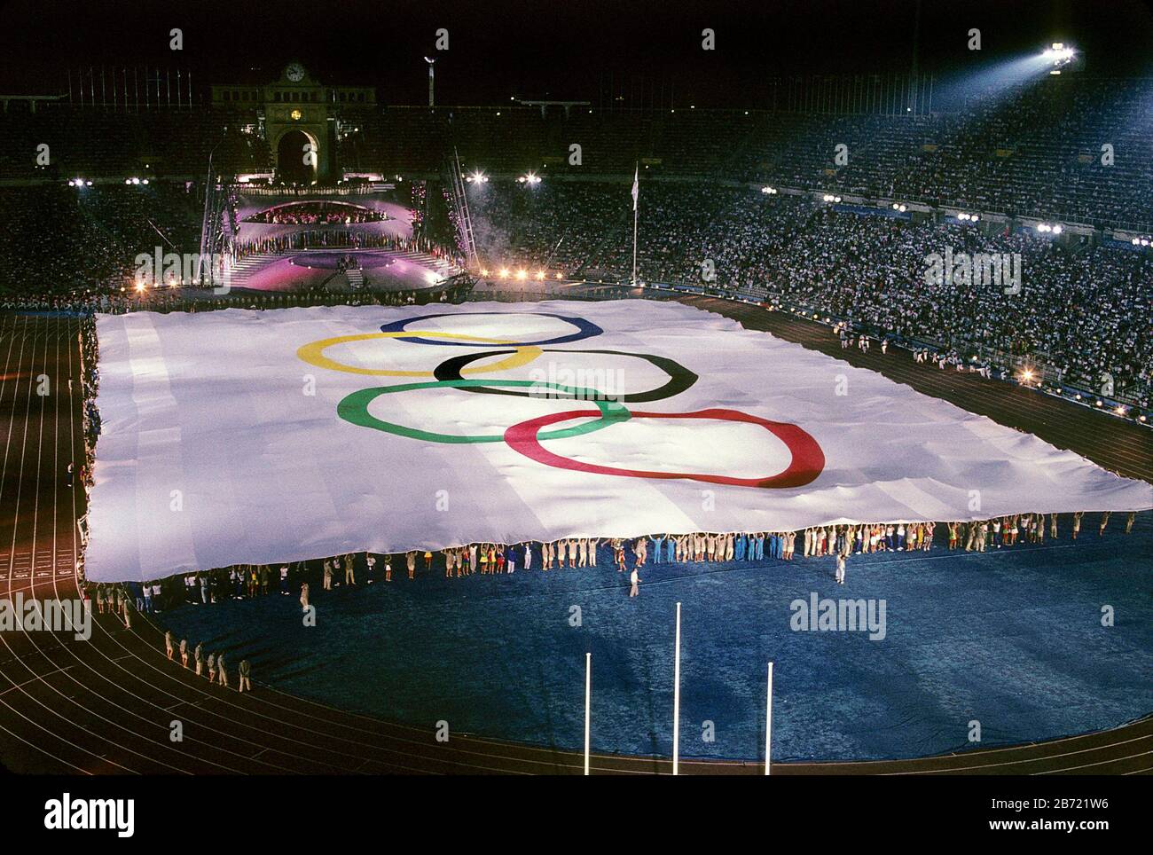 Barcelone, Espagne, 1992: Des centaines de personnes tiennent les bords de l'énorme drapeau olympique sur le terrain au stade Montjuic lors des cérémonies d'ouverture des Jeux Olympiques d'été. ©Bob Daemmrich Banque D'Images