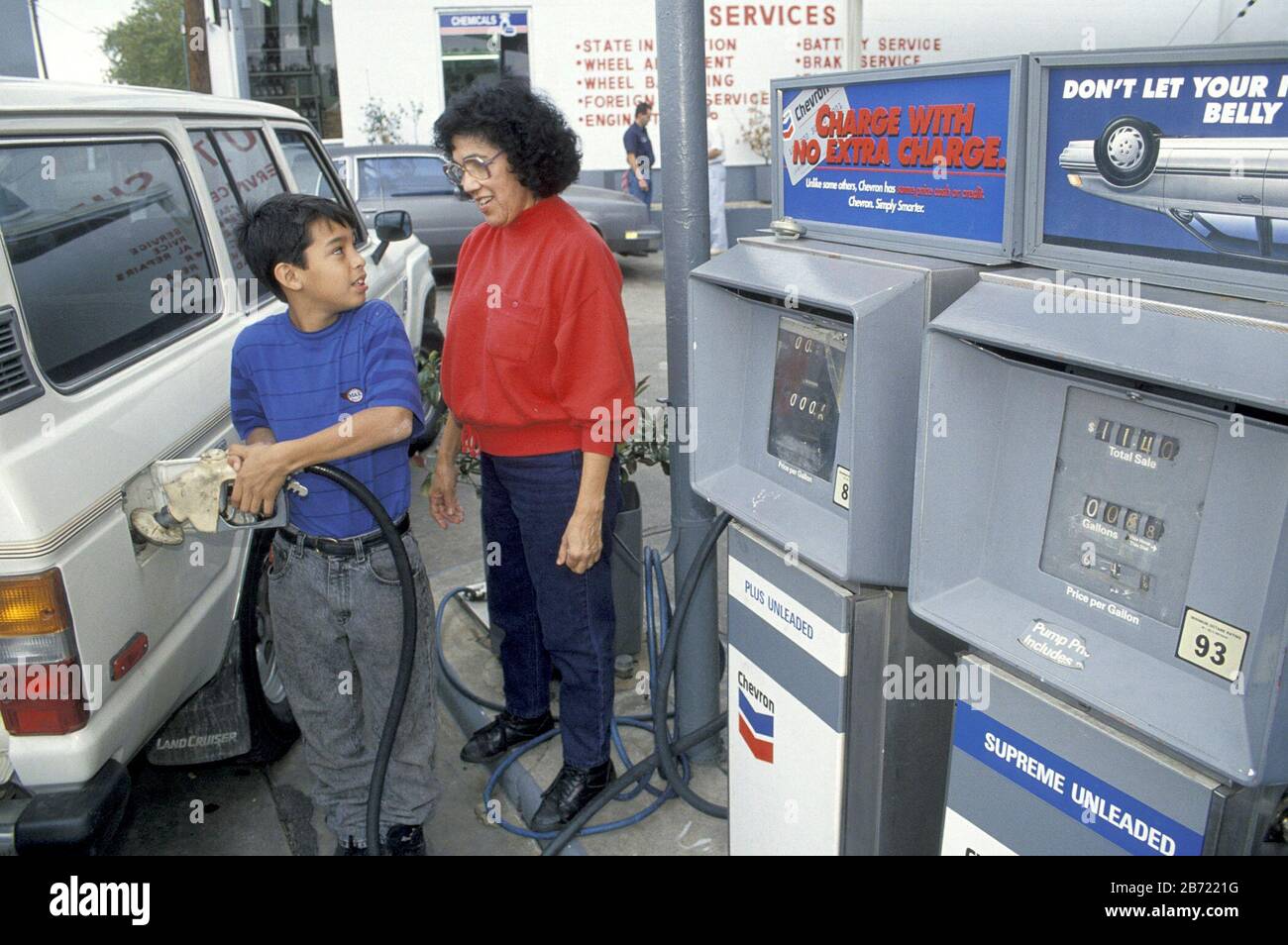 Austin, Texas États-Unis: Un garçon hispanique met du gaz dans le véhicule tandis que sa grand-mère regarde. M. ©Bob Daemmrich Banque D'Images