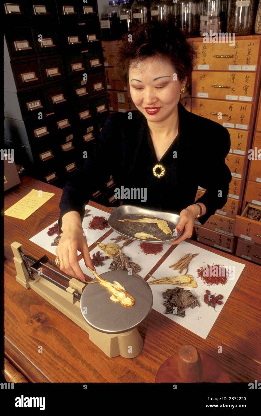 Austin, Texas USA: Herbes de broyage professionnelle de sexe féminin asiatique à la pharmacie chinoise dans la clinique d'acupuncture. ©Bob Daemmrich Banque D'Images