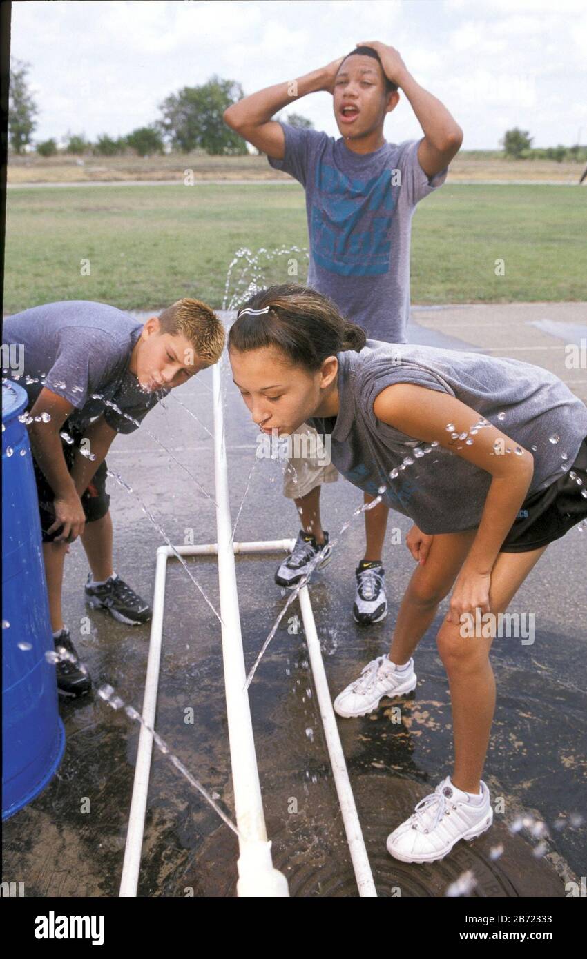 Pflugerville, Texas: Les enfants de l'école moyenne boivent de l'eau après s'exercer une journée chaude. ©Bob Daemmrich Banque D'Images