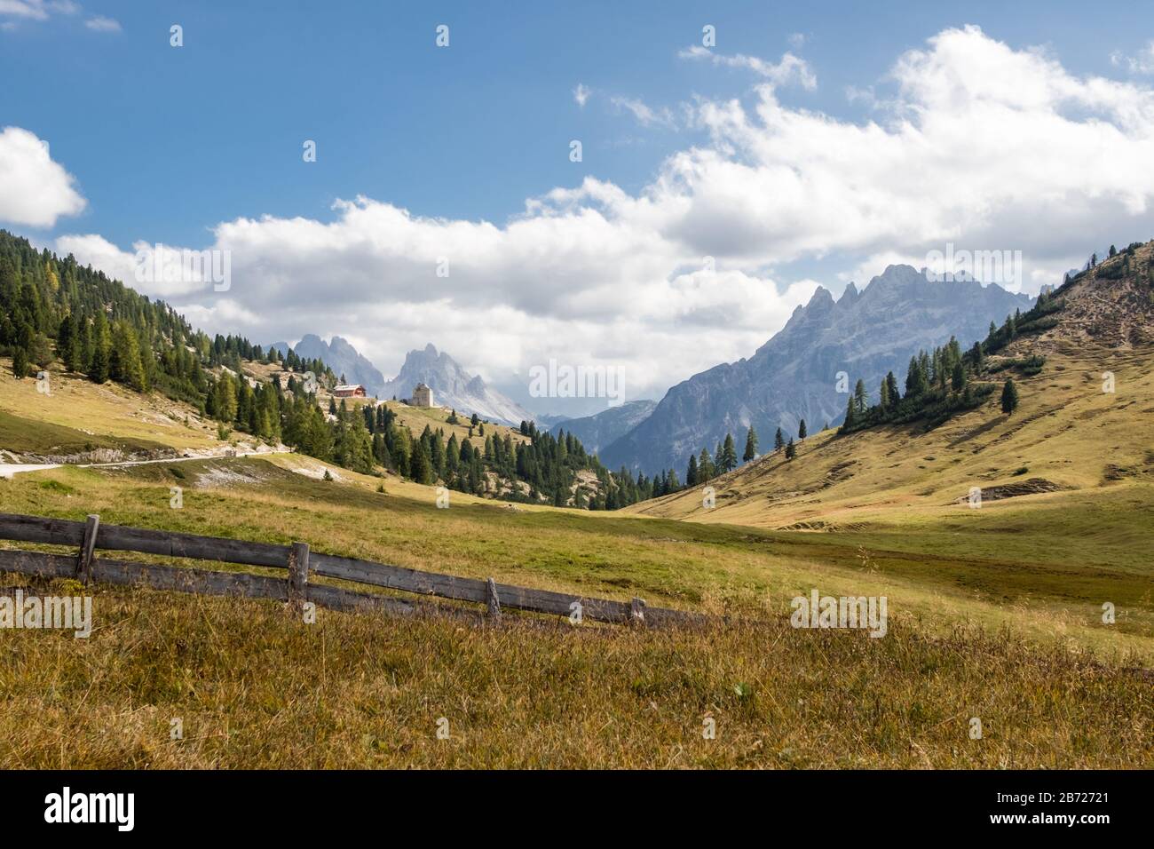 Vue sur les sommets déchiquetés des Dolomites italiens avec des prairies herbeuses et une clôture en premier plan. Banque D'Images