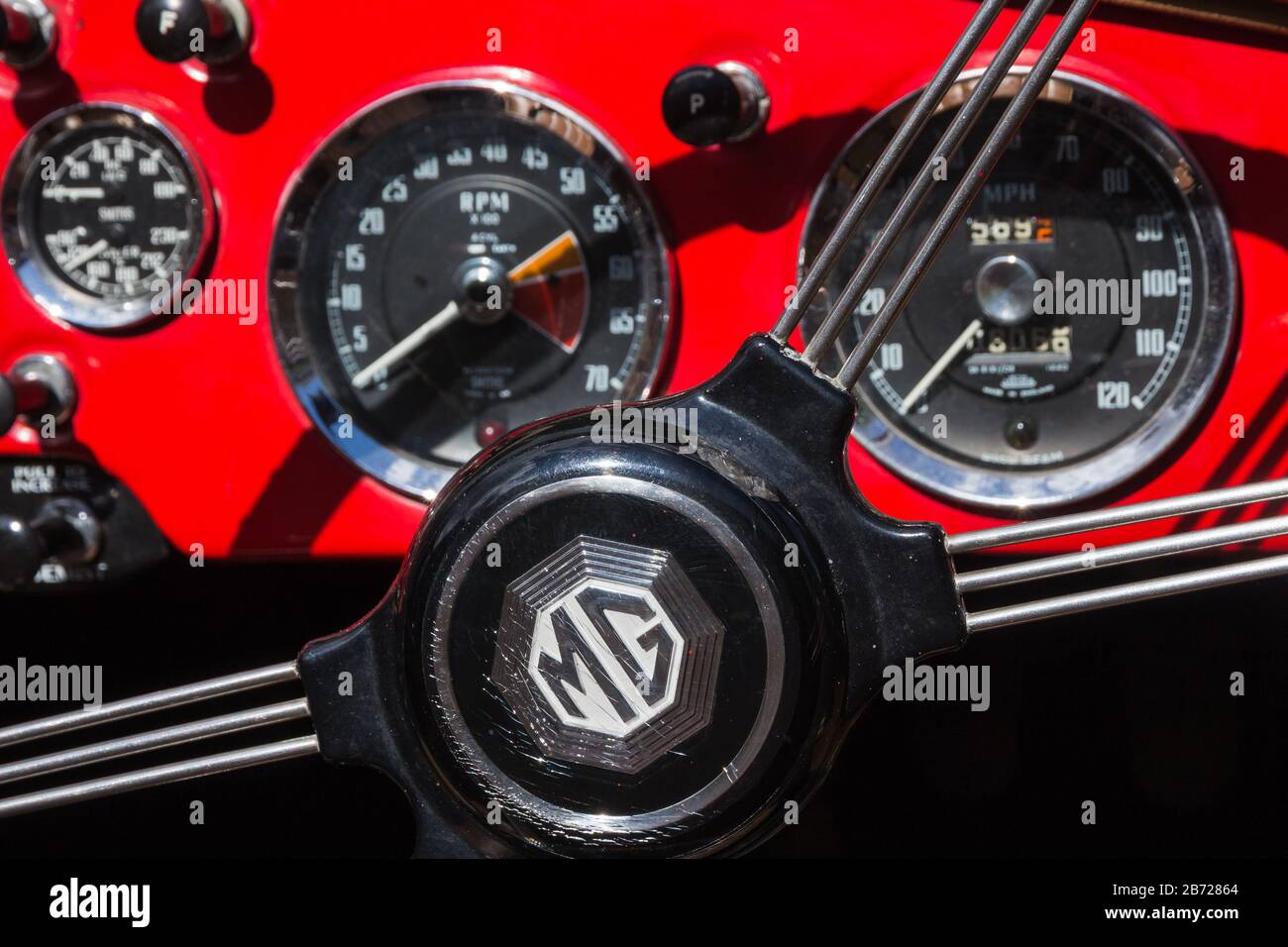 Centre du volant avec rayons en métal et tableau de bord rouge dans la classique britannique MG MGA SPAR affiché lors d'un rallye automobile à Oxfordshire, Royaume-Uni Banque D'Images