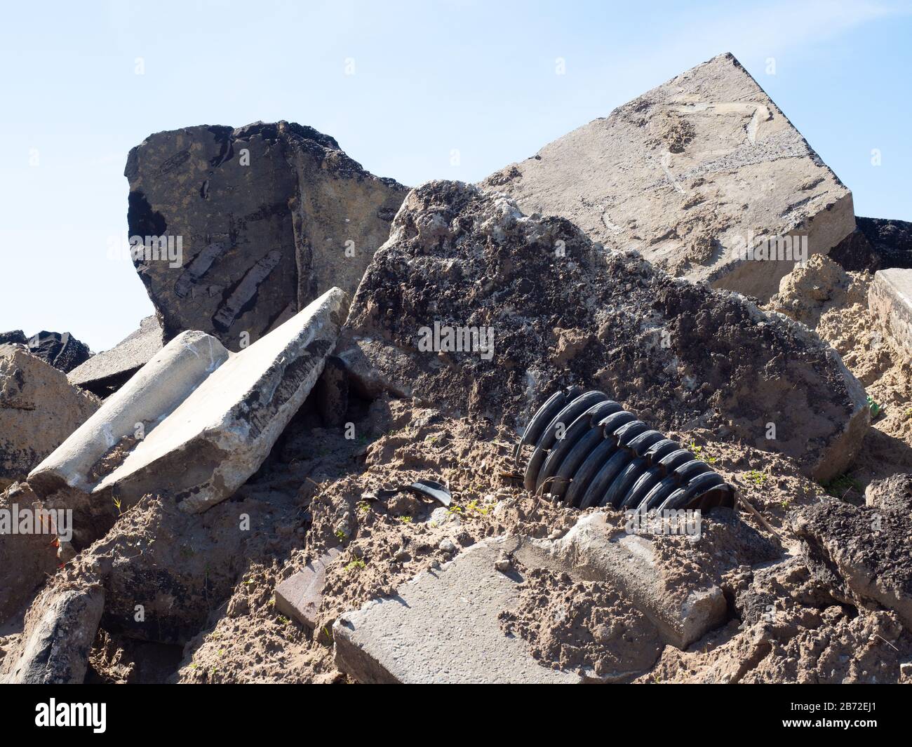 Débris de démolition de route pile, vue rapprochée de Rubble, corde de pile, bordure en béton, tubes en plastique striés noirs, béton, asphalte, gravier, sable Banque D'Images