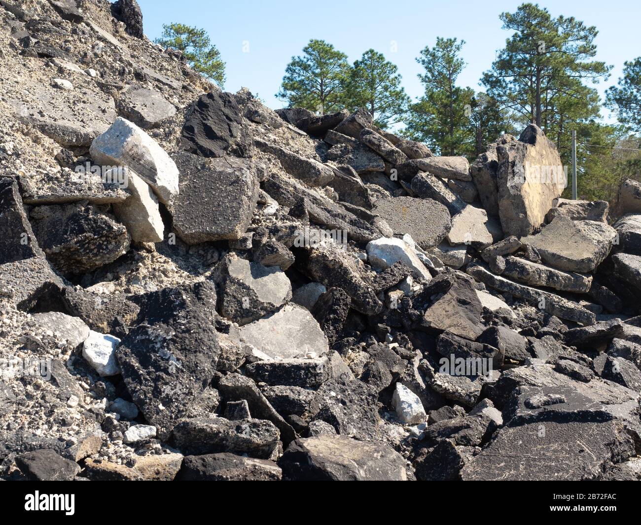 Montagne de débris de route, site de démolition de route Rubble, débris Pile sections massives de chaussée, asphalte, béton, agrégats, sable, pins derrière Banque D'Images