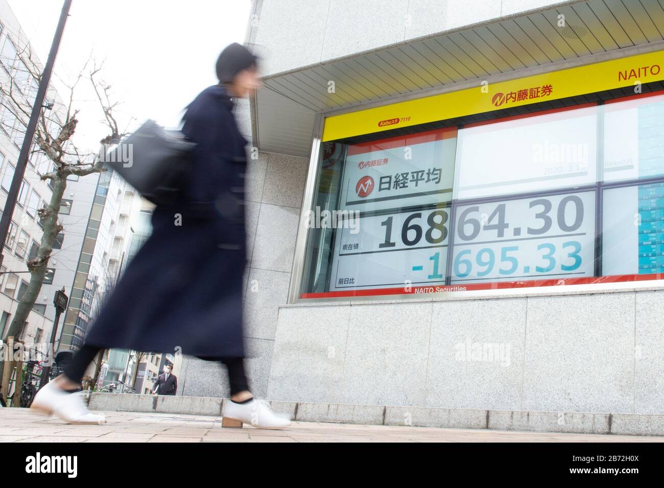 Tokyo, Japon. 13 mars 2020-. Une femme passe devant un tableau électronique montrant La Moyenne des stocks de Nikkei au Japon à Tokyo, au Japon, le 13 mars 2020. Les actions japonaises ont plongé de plus de 10 % lors de la séance du matin sur le marché de la Bourse de Tokyo après la plus forte chute de Wall Street depuis l'accident du lundi noir de 1987. Crédit: Aflo/Alay Live News Banque D'Images