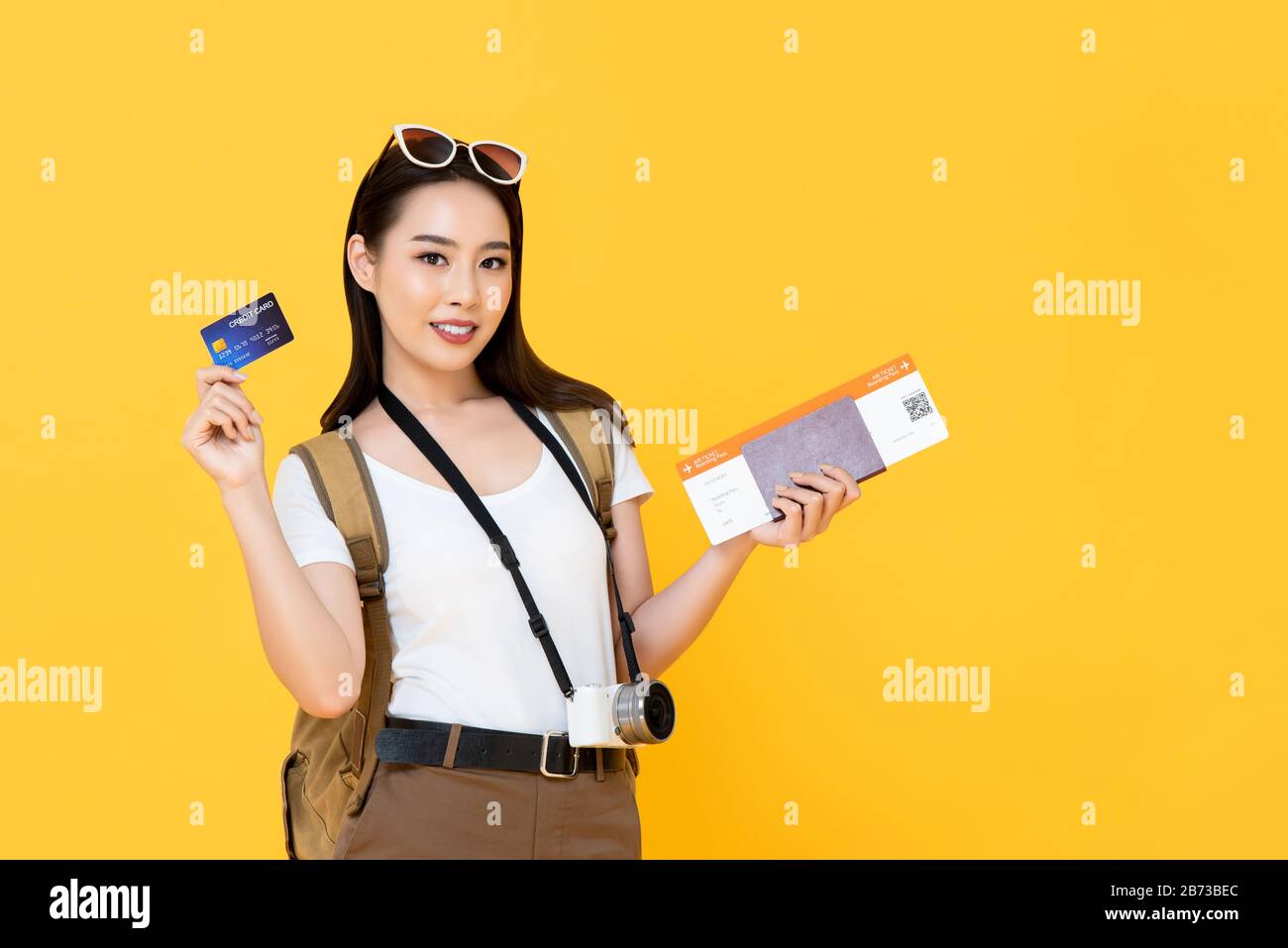 Belle femme de tourisme asiatique sur fond jaune avec passeport et carte d'embarquement prêts à voyager avec carte de crédit Banque D'Images