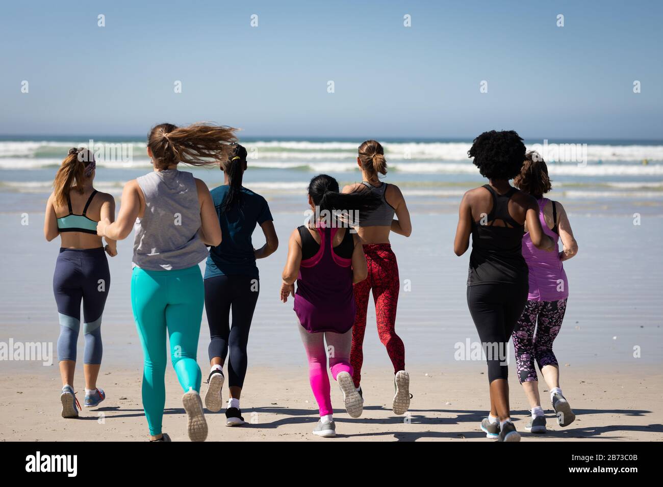 Vue arrière des femmes qui courir à la plage Banque D'Images