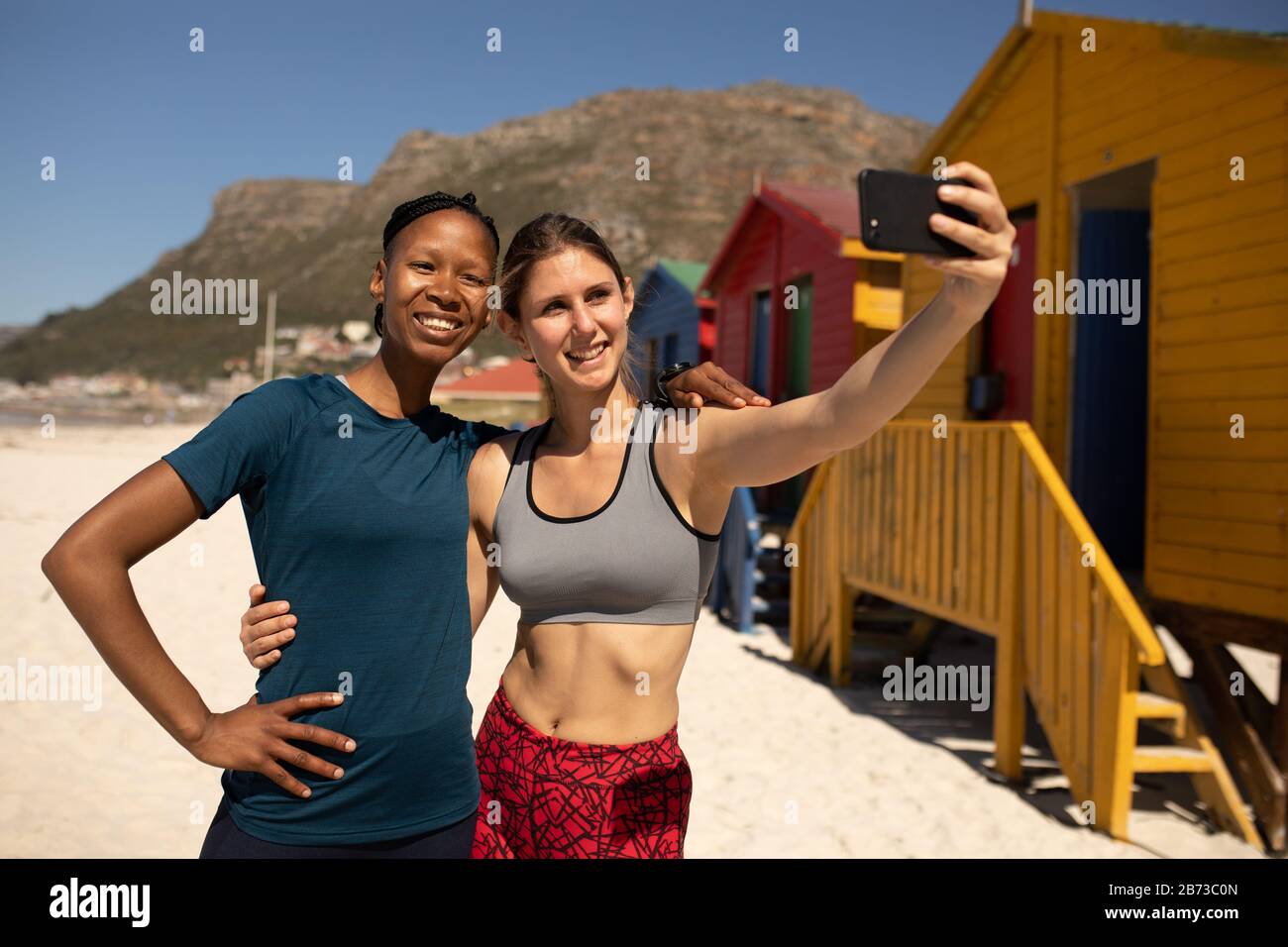 Vue de face d'amis prenant des selfies à la plage Banque D'Images